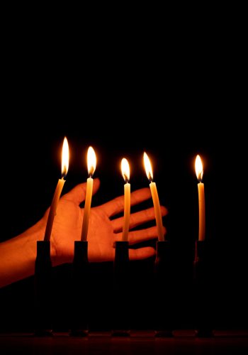 A woman s hand next to shell casings in which candles are burning in the dark, pain and loss of people, war in Ukraine